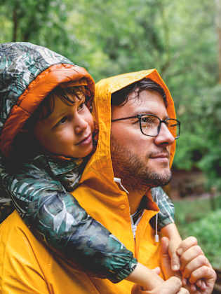 Vater und Sohn wandern an einem regnerischem Tag. © StockRocket/iStock / Getty Images Plus via Getty Images