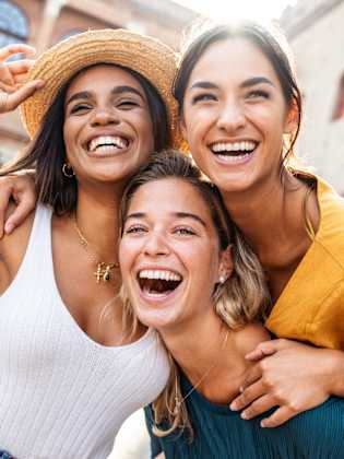 Drei Frauen strahlen in die Kamera