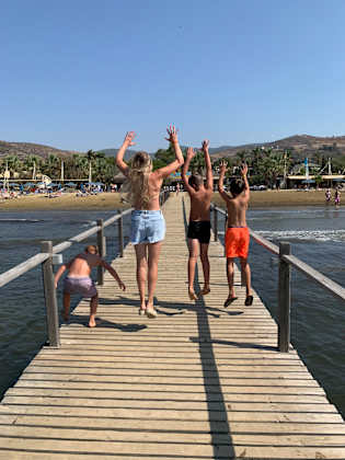Frau mit drei Jungs auf einen Steg im Meer.