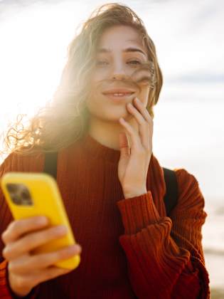 Frau mit Smartphone am Strand.