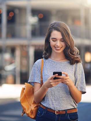 Frau schaut lächelnd auf ihr Smartphone