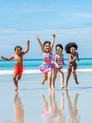 Eine fröhliche Kinderschar läuft am Strand entlang.
