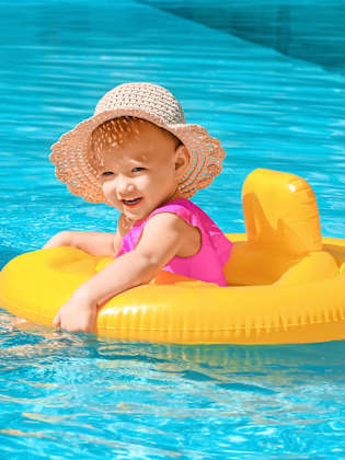 Kleines Mädchen in Pool in einem gelben Schwimmring.