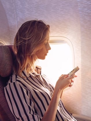 Frau mit Handy im Flugzeug