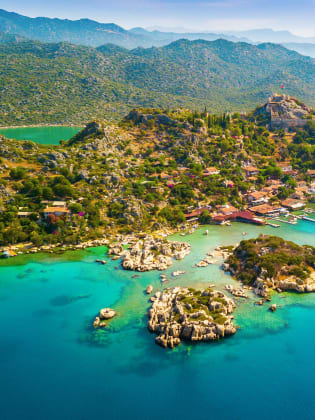 Blick auf die Weite der Türkischen Riviera mit grüner Landschaft. Im Vordergrund ist das blaue Meer zu sehen.