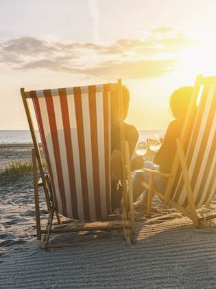 Zwei Personen in Liegestühlen im Sonnenuntergang am Ostseestrand
