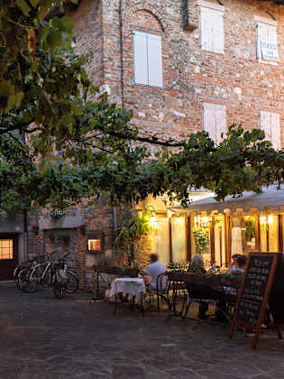 Altstadtgassen  mit großem Baum und Restaurant in Grado am Abend