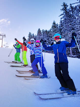 Skischüler stehen am Hang auf der schneebedeckten Piste.