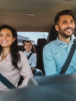 Familie sitzt gut gelaunt im Auto.