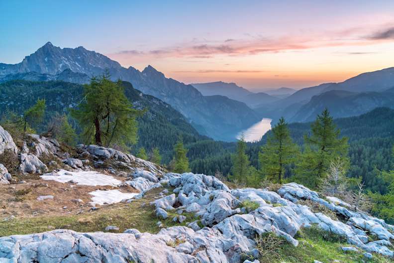 Blick auf ein Gebirge mit Bäumen bei Sonnenuntergang