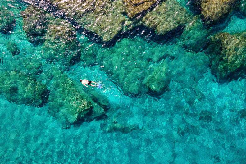 Ein Mann, der im Sommer im smaragdgrünen Wasser der Ägäis auf der griechischen Insel Andros © iStock.com/SHansche