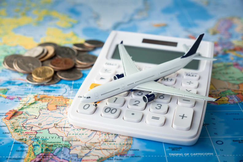 Flugzeug auf einem Taschnerechner mit Kleingeld auf einer Weltkarte © iStock.com/Sezeryadigar