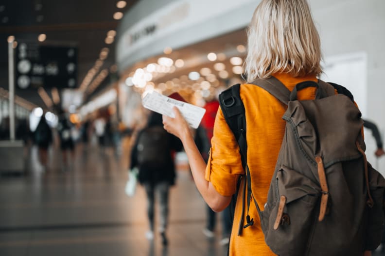 Frau mit Flugticket und Rucksack am Flughafen © iStock.com/Pyrosky
