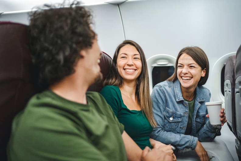 Freunde lachen im Flugzeug © Viktor Cvetkovic/E+ via Getty Images