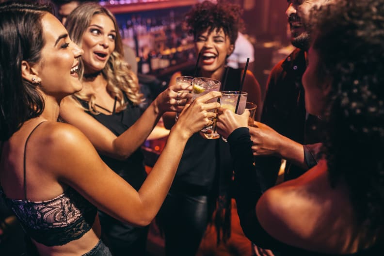 Eine Gruppe von Freunden stößt mit Cocktails in einem Nachtclub an. © jacoblund/iStock / Getty Images Plus via Getty Images