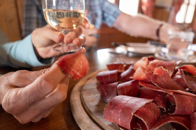 Gruppe von Freunden teilt sich eine Tafel getrockneter Fleischscheiben © iStock.com/K Neville