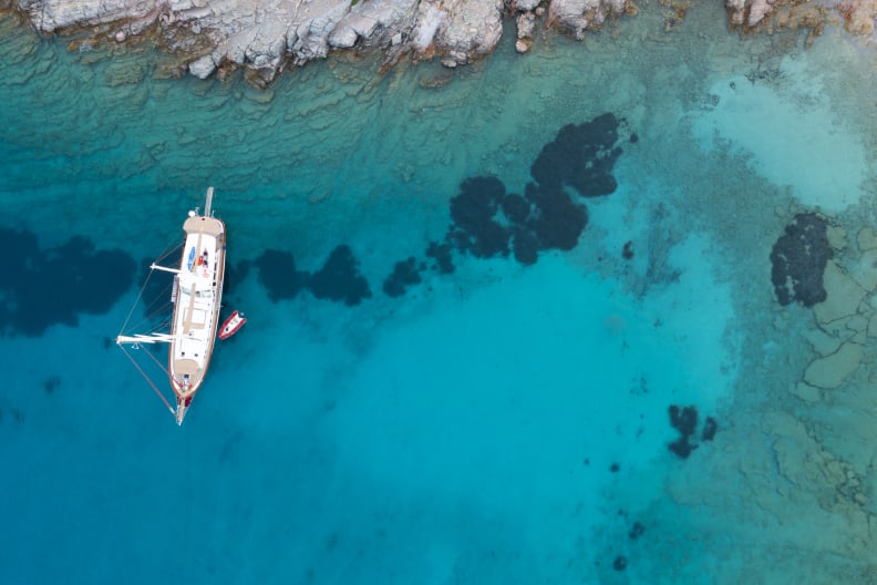 Luftaufnahme von einem Segelschiff in türkisfarbenem Meer © iStock.com/bodrumsurf