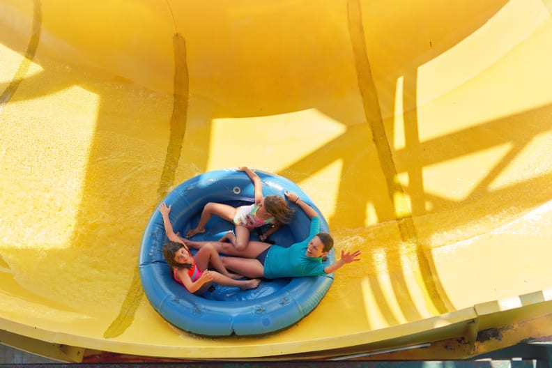 Mädchen fahren in einem Ring auf einer Wasserrutsche. © Sebastian Condrea/Moment via Getty Images