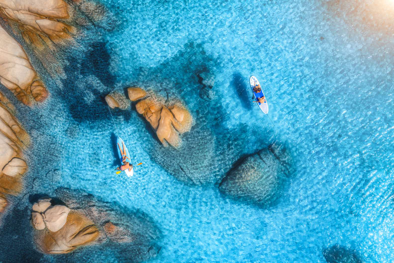 Menschen auf schwimmendem Kanu im transparenten azurblauen Wasser, Insel Sardinien © iStock.com/den-belitsky