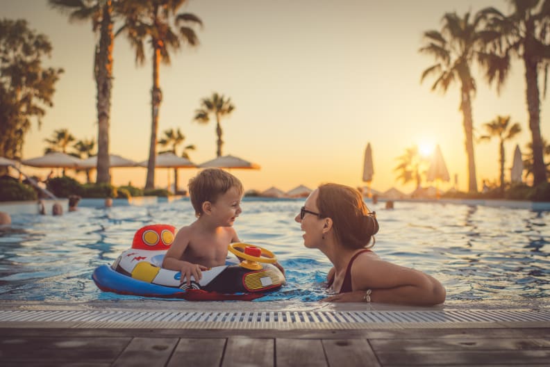Mutter mit ihrem Kind im Pool beim Sonnenuntergang © iStock.com/ArtMarie