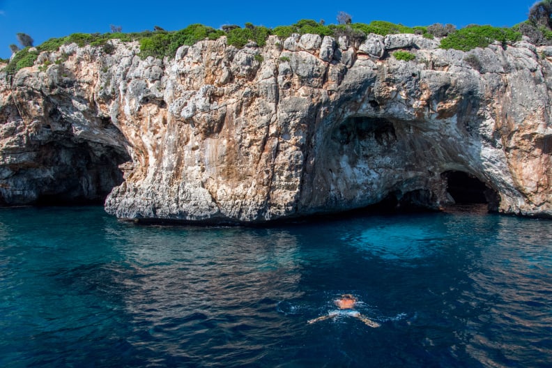 Person taucht zu einer Höhle an der Küste Mallorcas im Mittelmeer © iStock.com/Thomas Bernd