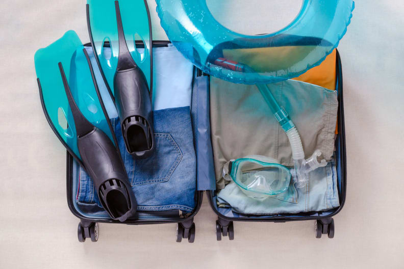 Reisekoffer mit Kleidung und Flossen und Schnorchelmaske für eine Reise © iStock.com/nadisja
