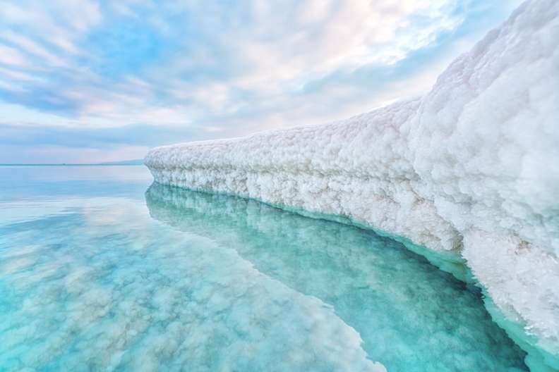 Sandbank bedeckt mit kristallinem Salz vom Toten Meer im hellblauen Meer vor ʿEin Bokek in Israel.