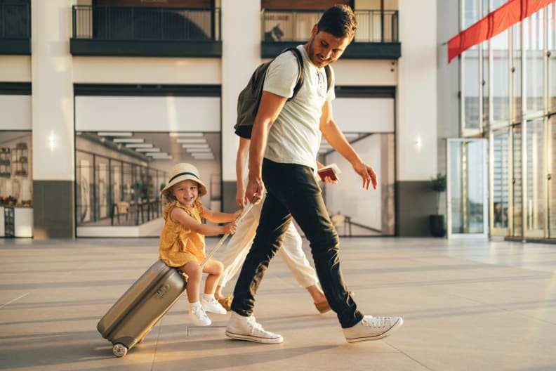 Vater zieht Kind, dass auf seinem Koffer sitzt durch den Flughafen © iStock.com/miniseries