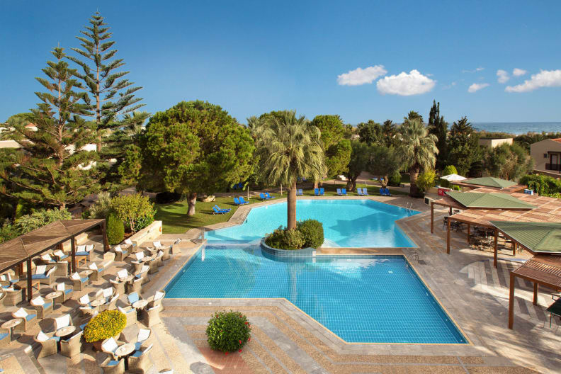 Blaues Poolbecken, Sitzmöglichkeiten, Sonnenschutz und Garten im Hotel Cretan Malia Park auf Kreta in Griechenland