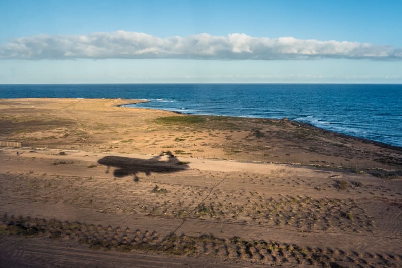 Der Schatten eines Flugzeugs über einer Küste.