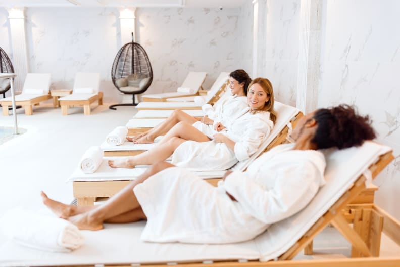 Drei Frauen entspannen an einem Pool. © Anchiy/E+ via Getty Images