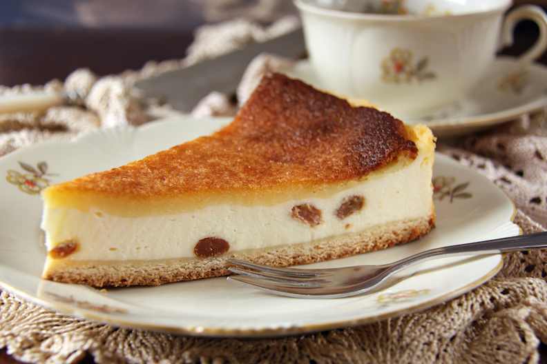 Ein Teller mit einem Käsekuchen mit Rosinen und einer Gabel