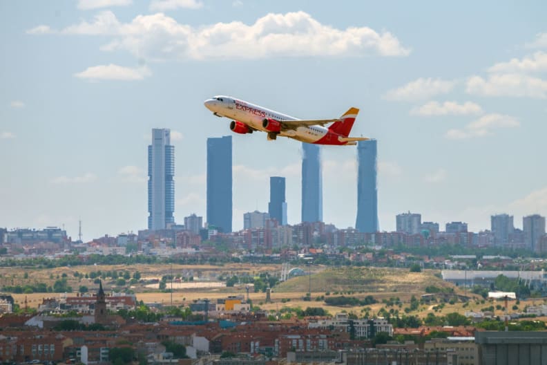Ein Flugzeug fliegt vor der Skyline von Madrid, Spanien.