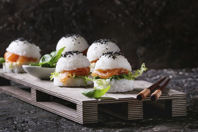 Ein Holzbrett mit mehreren Sushi-Burgern.
