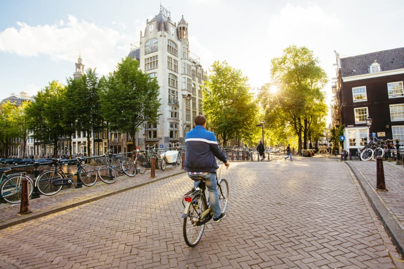 Ein Mann fährt mit dem Fahrrad über eine Brücke in Amsterdam.