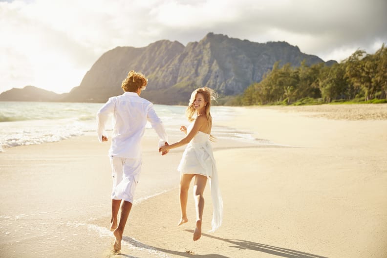 Ein Paar rennt gemeinsam einen Strand entlang.