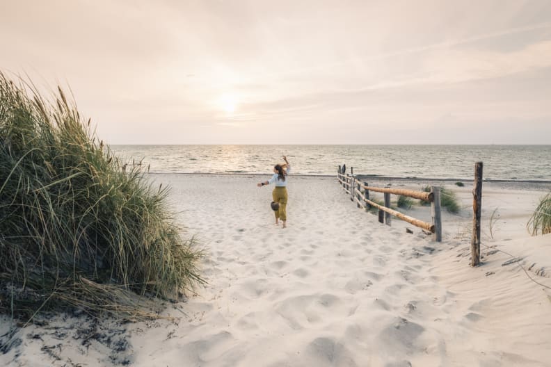 Eine Frau rennt einen Strand in Mecklenburg-Vorpommern, Deutschland, entlang. © Francesco Vaninetti Photo/Moment via Getty Images
