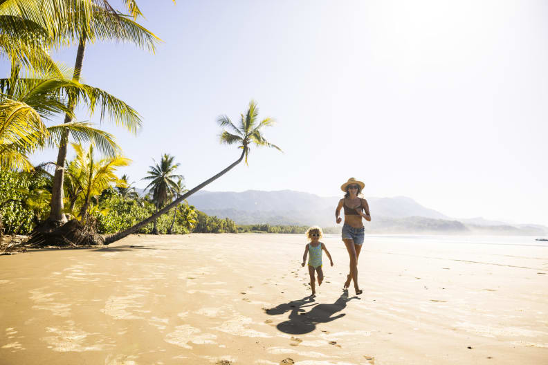 Eine Frau rennt mit ihrem Kind an einem Strand entlang © Jordan Siemens/DigitalVision iva Getty images