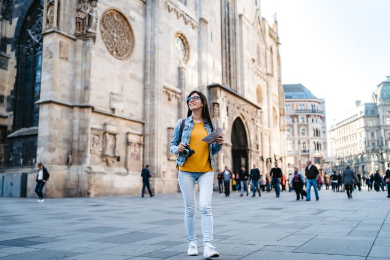Eine Frau steht mit Stadtplan und Kamera in Wien.