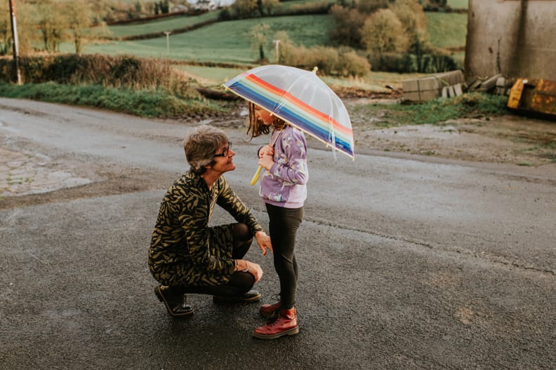 Eine Großmutter kniet vor ihrer Enkelin, die einen Regenschirm hält. © Catherine Falls Commercial/Moment via Getty Images