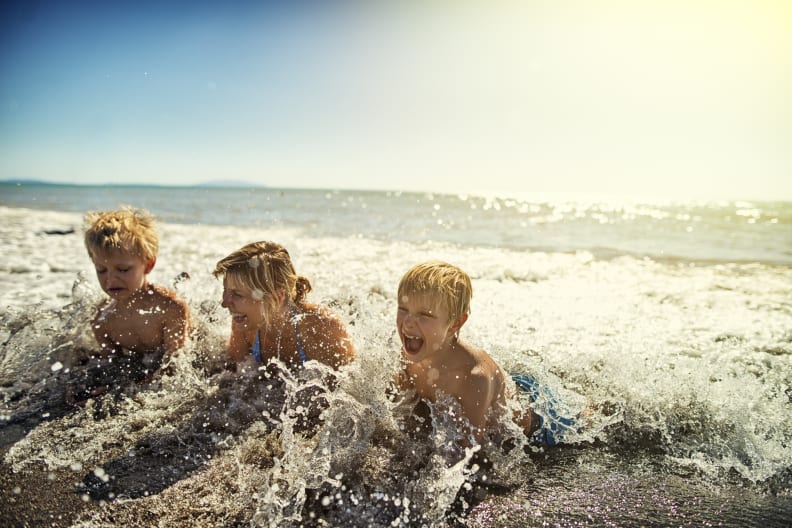 Familie liegt am Strand und planscht in Meereswellen in der Toskana, Italien