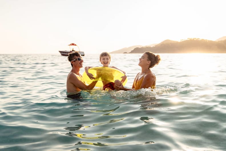 Eine Familie planscht glücklich im Meer.
