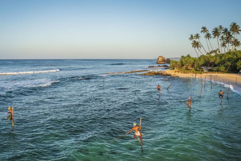 Fischer auf Stelzen im Meer in Thailand.