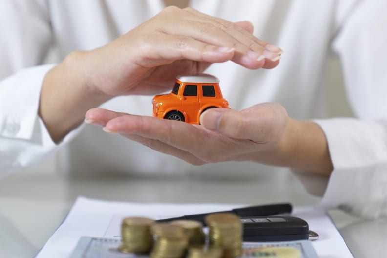 Eine Frau hält ein Spielzeugauto in den Händen, im Vordergrund liegt Geld.
