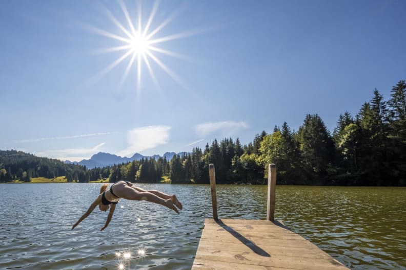 Eine Frau macht einen Kopfsprung in den See, Bayern, Deutschland.