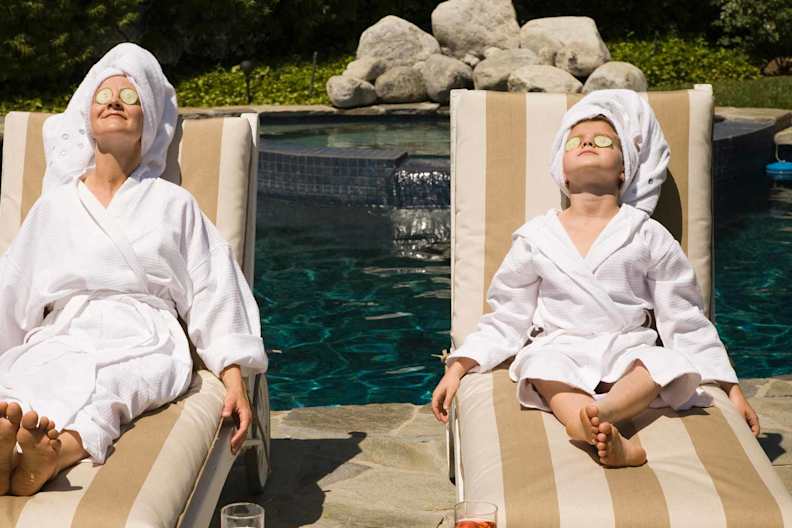 Frau und Kind entspannen mit einer Gurkenmaske im Gesicht am Pool.