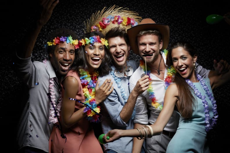 Lachende Freunde tragen Girlanden in einem Nachtclub. © Morsa Images/DigitalVision via Getty Images