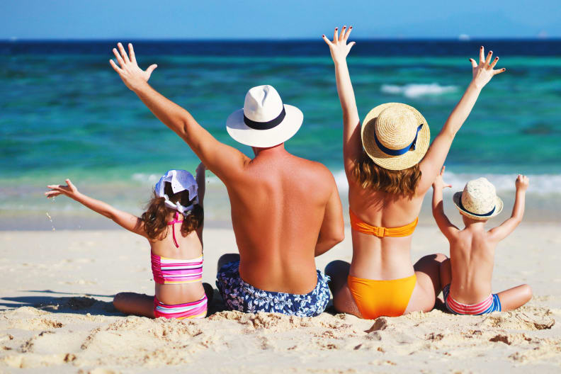 glückliche Familie mit Vater Mutter und Kindern sitzen am Strand © iStock.com/evgenyatamanenko