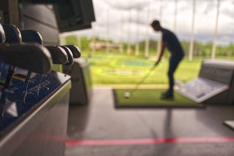 Eine Sammlung Golfschläger und ein Golfer im Hintergrund