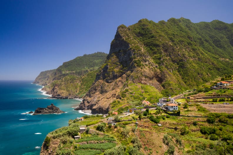 Grüne Berge auf Madeira, die bis zum Meer reichen.
